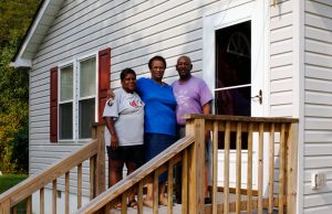 Happy family standing in front of home