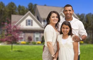 Hispanic family standing in front of house.